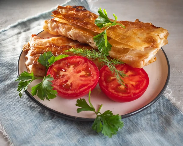 Plate with baked homemade sandwiches and red tomato halves, side view