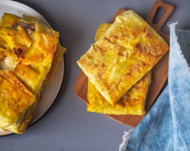 Et ve sebze ile sıcak pişmiş sandviçler, ahşap bir tabakta hizmet veren, bir peçete altında bir tabak sandviç yığını, yakın çekim görünümü