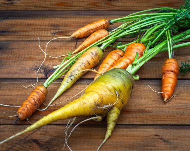 Ahşap bir tahta masada yeşil üstleri ile Hasat havuç