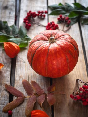 Sonbahar, portakallı balkabağı fisalisiyle, tahta bir masada, dikey çerçevede.