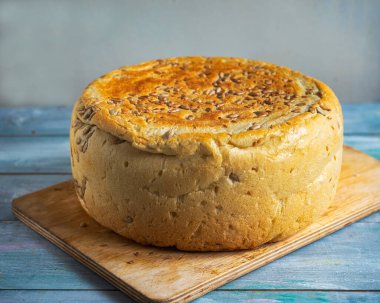 Mutfak tahtasının üzerinde tohum olan büyük bir somun ev yapımı ekmek.