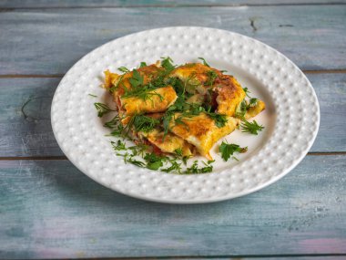 Omletli, domatesli ve beyaz tabakta taze otlu hızlı besleyici kahvaltı.