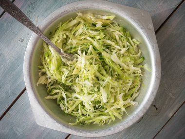 Lahanalı hafif diyet salatası, çatallı metal bardakta ince dilimler, ahşap bir masanın üst görüntüsü.