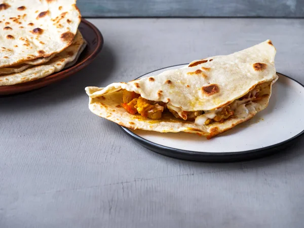 Fast Food, Quesadia mit Huhn und Gemüse auf einem runden hellen Teller und gebackenen Tortillas in einem Teller — Stockfoto
