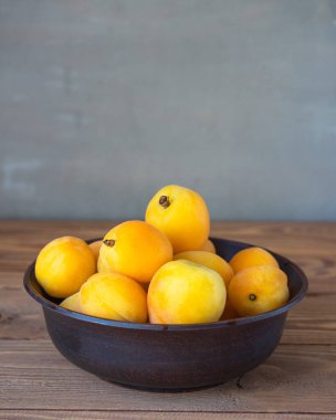 Ahşap bir masada, derin bir klozetin içinde olgun kayısılar.