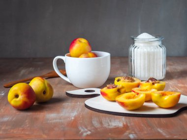 Nektarinlerden reçel yapma seti. Kırsal bir mutfak masasında cam bir kavanozda dilimlenmiş nektarin ve şeker.