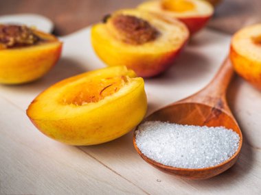 Nektarin yarımları ve ahşap kesme tahtasında şekerli ahşap kaşık.