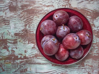 Kahverengi ahşap masa manzaralı kırmızı erikli tabak.