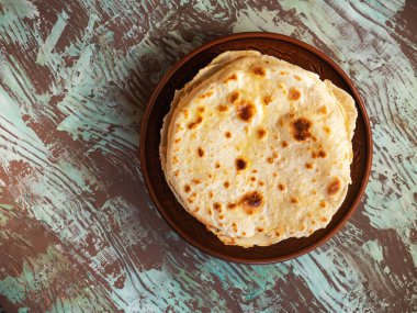 Pita yapmak için düz ekmek çeşitlendirilmiş kahverengi arka plan görünümünde kahverengi bir kil plaka üzerinde uzanır