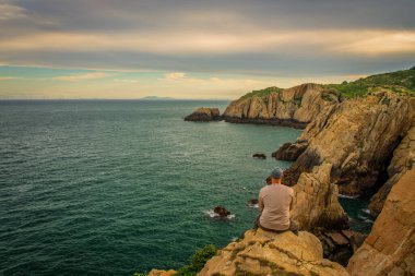 Man alone sitting on the cliff enjoy the view