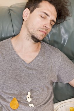 bir sürü abur cubur bir kanepede uyuyan bir adam