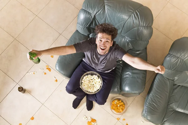 A young man watches match on television while relaxing