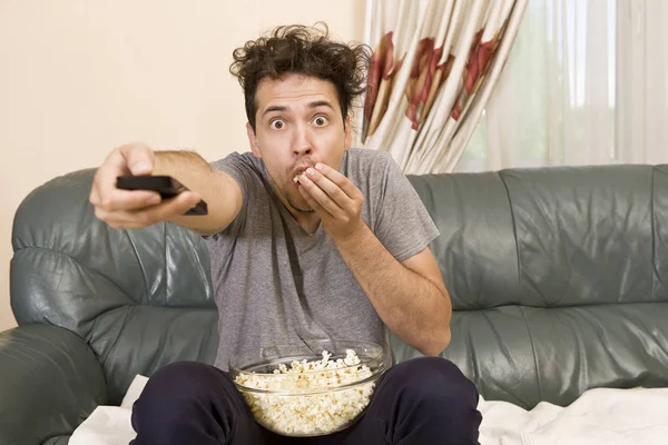Man with beer and popcorn watching TV at home