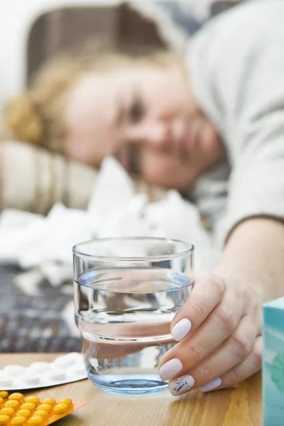 患有头痛 感冒和流感的年轻妇女拿着一杯水 — 图库照片