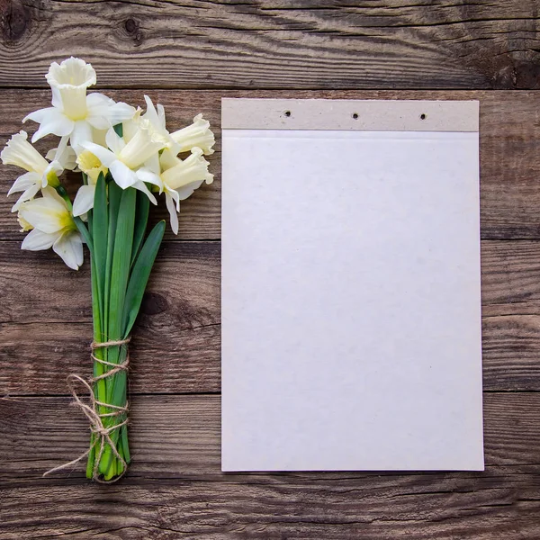Narin sarı-beyaz nergis ve plan kopya alanı ile ahşap bir yüzey üzerinde kaydetmek için bir kağıda bir buket ile kare resim