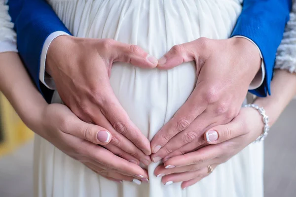 心脏从怀孕夫妇的手掌在白色礼服特写的腹部 — 图库照片