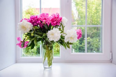 Güzel pencere üzerinde bir vazoda beyaz ve pembe peonies buket