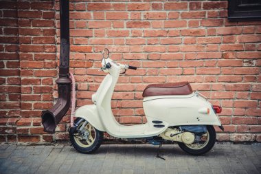 Kırmızı tuğla duvara şehirde sokakta beyaz küçük scooter