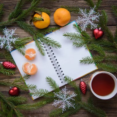 Yeni yıl ve çam dalları, kar taneleri, mandalina, çay, Noel şenlikli resmi bir ahşap rustik arka plan üzerinde not defteri açın