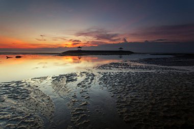 Sanur, Endonezya 'nın Bali adasının güneydoğusunda bir sahil kasabasıdır. Kumsalın uzun uzantısı sığ suları sunuyor. Kumda renkli jukung balıkçı tekneleri dinleniyor.,