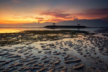 Sanur, Endonezya 'nın Bali adasının güneydoğusunda bir sahil kasabasıdır. Kumsalın uzun uzantısı sığ suları sunuyor. Kumda renkli jukung balıkçı tekneleri dinleniyor.,