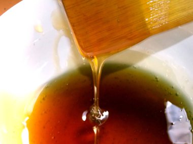 Bir tahta kaşık bir kasenin içine damlayan tatlım. Doğal ve lezzetli bal.