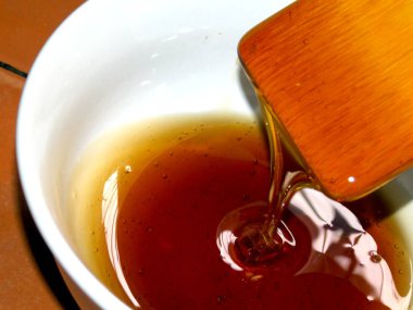 Tahta kaşık bir kapta bal damlıyor. Lezzetli tatlım