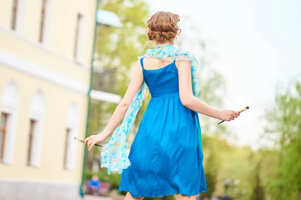 Belle artiste fille dans la rue en robe bleue, avec pompon à la main du dos — Photo