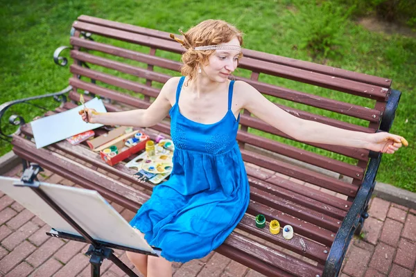 Mooi meisje-artiest op de straat in een blauwe jurk, verspreidt zijn handen aan de zijkanten — Stockfoto