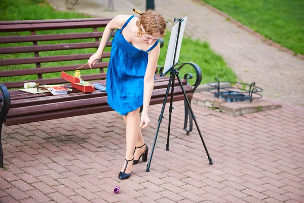 Όμορφο κορίτσι-καλλιτέχνης στον δρόμο, σε ένα μπλε φόρεμα αυξάνει την πέσει χρώμα — Φωτογραφία Αρχείου