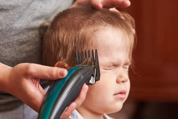 A man cuts machine child at home. — Stock Photo, Image