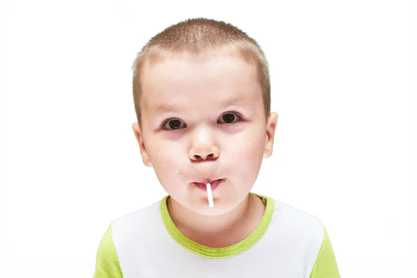 Un niño pequeño con un bastón de caramelo en la boca . — Foto de Stock