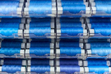 Dükkandaki standda mavi dikiş iplik makaraları, seçici odak, arka plan dokusu