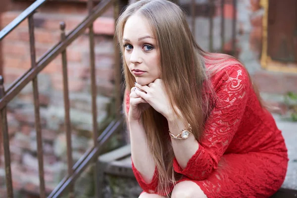 Красивая блондинка в красном платье на ступенях старого здания — стоковое фото