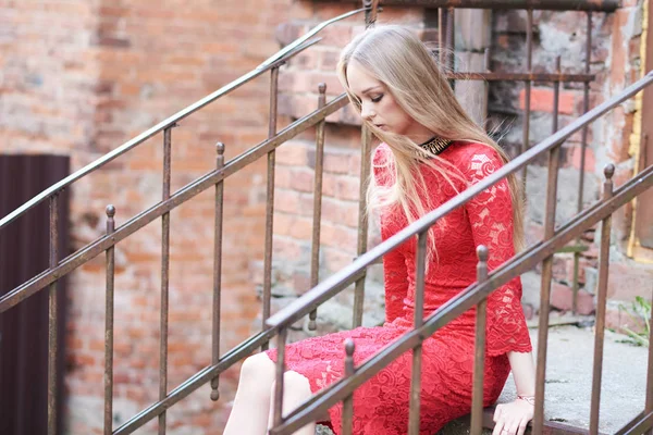 Bella ragazza bionda in un vestito rosso sui gradini di un vecchio edificio — Foto Stock