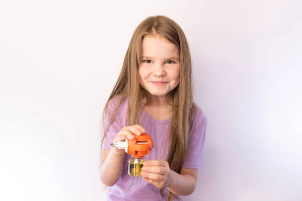 Bambina che tiene un fumigatore dalle zanzare e sorride su sfondo chiaro — Foto Stock