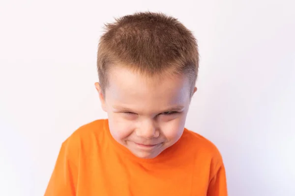Piccolo ragazzo carino, guardando sospettosamente da sotto la fronte, su uno sfondo leggero — Foto Stock