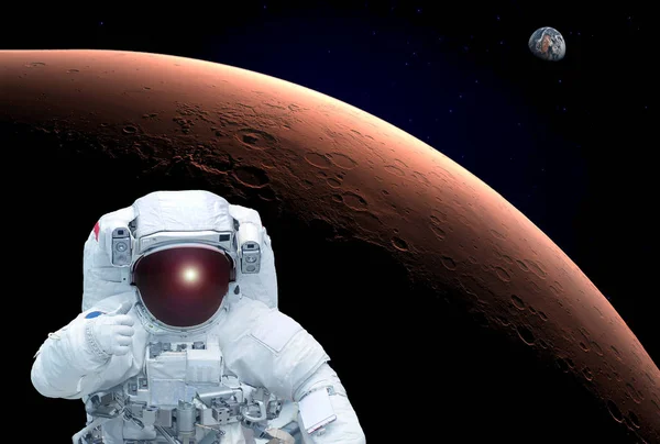 The astronaut in an orbit of Mars, shows the sign a class, Earth is in the distance visible. Elements of this image were furnished by NASA — Stock Photo, Image