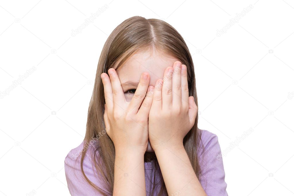 The little girl closes her eyes with her hands, but peeps. Isolated on a white background.