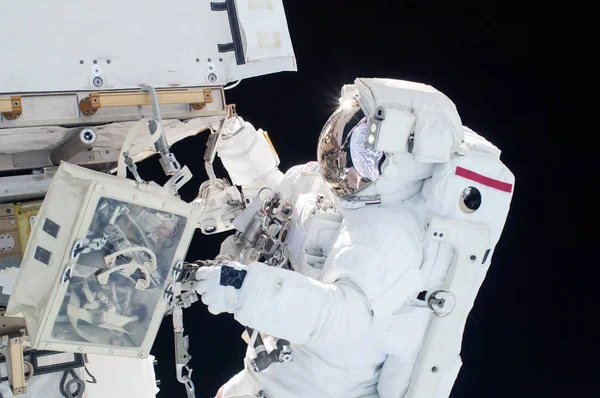 Astronauten i en rymddräkt, i ett yttre rymden, är engagerad i reparation av rymdstationen. Delar av denna bild möblerades av NASA — Stockfoto