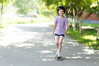 Küçük bir kız sokakta kayıyor. Ve gülümsüyor.