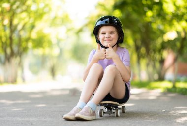 Küçük olan kaykayın üzerinde oturuyor, yüzünde komik bir ifade olan bir sınıf işareti gösteriyor..