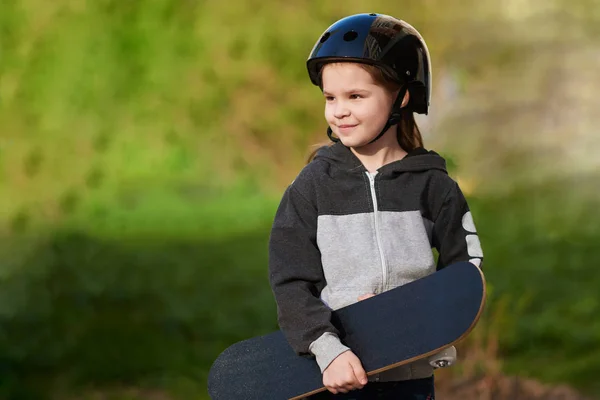 Menina com um skate e em um capacete . — Fotografia de Stock