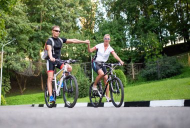 Erkek ve kadın el ele bisiklete biniyor.