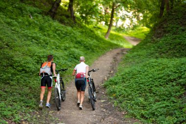 Bisikletli erkek ve kadın yokuş yukarı tırmanıyor