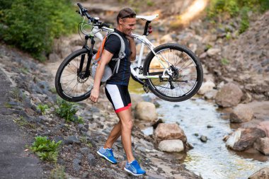 Omzunda bisiklet olan bir adam nehri geçer ve elini uzatır..