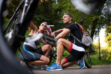 Spor adam ve kadın poz oturan, bisiklet bir arka plan üzerinde.