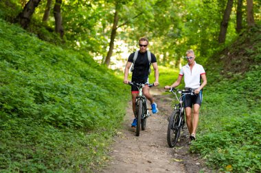 Bisikletli bir adam ve bir kadın tepeden aşağı iner..