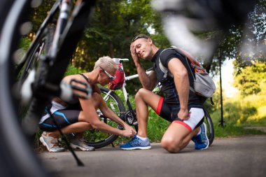 Bir kadın bisiklet arka plan üzerinde spor ayakkabı bir adam ayakkabı bağcıkları bağlar.