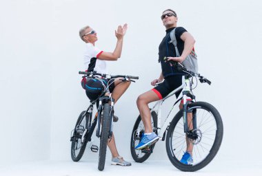 Bir kadın bir adamı alkışlar, her ikisi de hafif bir arka plan üzerinde bisikletle..